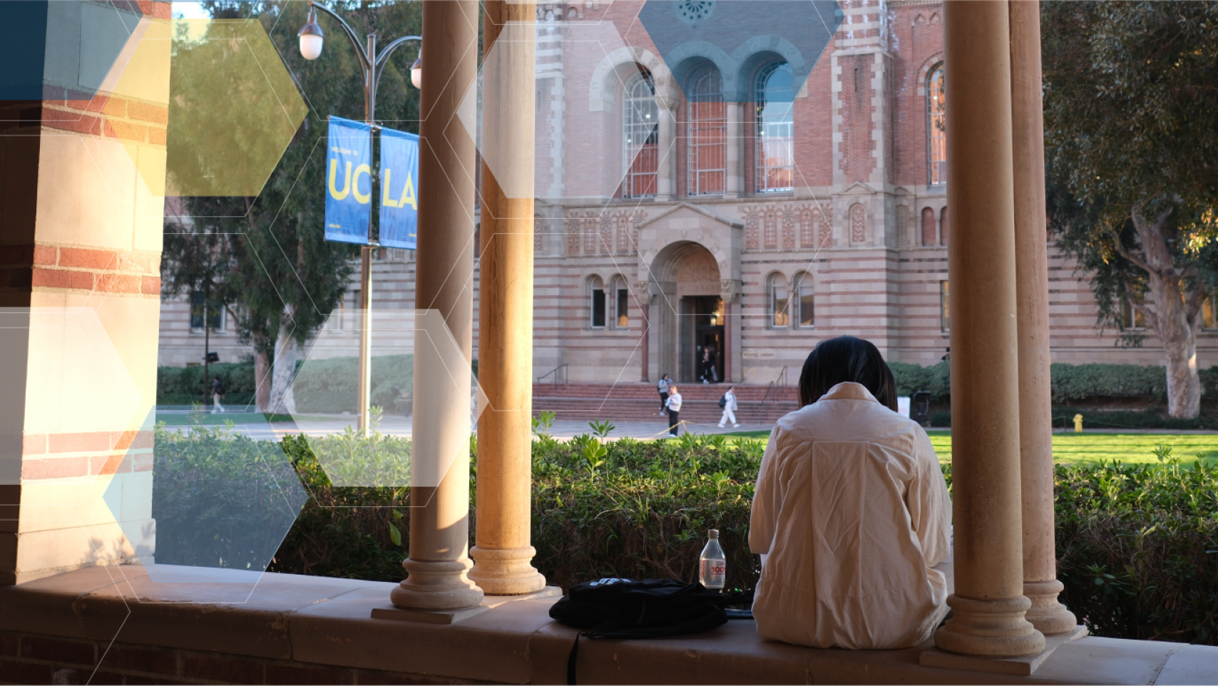 A student sits in the Royce breezeway overlooking Powell Library with blue, yellow, and white molecule overlay